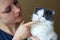 Woman brushes cat`s teeth with a toothbrush on her finger