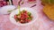 The woman brushes the cut tomatoes from the cutting Board into a plate of sliced vegetables with a knife