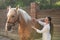 Woman brushing adorable horse outdoors. Pet care