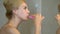 Woman brushing teeth in front of mirror in bathroom, dental care, oral hygiene