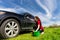 Woman with Bucket Washing Black Car in Field