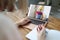 Woman builder in protective helmet waving hand from laptop screen to client