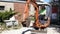 Woman builder wearing hard hat drives an excavator at building site smiling doing thumb up sign.