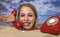 Woman buried in sand on beach with telephone