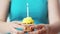 Woman with burning candle on birthday cupcake