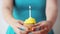 Woman with burning candle on birthday cupcake