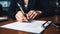 a woman in a business suit signing into an order with a pen and paper