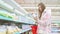 Woman buyer choosing buying bottle of milk in dairy food department in mall.