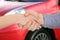 Woman buying car and shaking hands with salesman against blurred auto