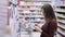 Woman buys goods by shopping list in supermarket