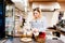 Woman cafe worker adding sugar to bowl with dessert