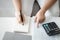 Woman is calculating annual tax with calculator and filling form of Individual Income Tax Return. Season to pay Tax and Budget