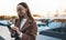 Woman calling mobile phone in Barcelona at sunset. Girl in glasses using smartphone technology. Digital business communication