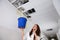 Woman Calling Plumber While Holding Bucket Under The Ceiling