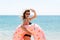 Woman calls to swim in the sea and waves her hand. Girl relaxing on inflatable ring at the beach. Summer holidays and vacation