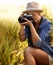 Woman, camera and photography with summer, vacation and holiday with wheat field and travel. Nature, photographer and