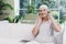 A woman with cancer is sitting on a white sofa in a modern clinic. She has a pink ribbon on her shirt.