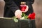 Woman with candle near black granite tombstone, focus on red rose. Funeral ceremony