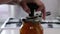 A woman cans apple jam at home. Closes the glass jar with a metal lid with rolling tool. Closeup.