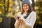 Woman in cap and glasses is holding mushrooms in hands in autumn forest