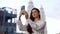 Woman captures video on her phone with a smile talking on a video call against a backdrop of skyscrapers in the