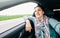 Woman in car portrait with wavy hair looks out car window wide angle shot