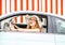 Woman in the car on red wall background