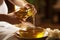 A woman carefully pours oil from a bottle into a bowl, likely for cooking or making a salad dressing, Therapist pouring massage