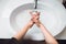 woman carefully washing hands with soap and sanitiser in home bathroom. top view, details of hygiene