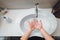 woman carefully washing hands with soap and sanitiser in home bathroom. top view, details of hygiene