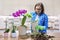 Woman caring for plant Phalaenopsis orchid, cutting roots, changing soil