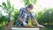 Woman carpenter peeling off old wooden plank with metal brush in backyard