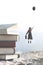 Woman carried by a balloon flies above a mountain of giant books