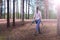 Woman carries felled trees to a forest scout`s camp for firewood, back view.