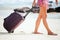 Woman carries your luggage at sandy beach