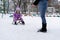 A woman is carrying a child on a sled. Mom walks with her daughter along a snowy path. Merry winter holidays. Winter fun