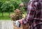 Woman carrying flower pot with blooming plant in garden