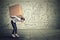 Woman carrying heavy box walking along gray wall