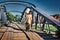 Woman carrying jerry can over metal colonial bridge in Myanmar asia