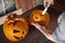 Woman carving Halloween pumpikn; Halloween pumpkin with a carved face