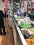 Woman cashier at cash regester wearing a protective disposable face mask at Aldi supermarket