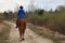 Woman in casual clothes rides a horse in early spring