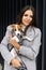 Woman in casual jacket hugging her favorite fluffy trained purebred Jack Russell Terrier dog dressed in suit for dogs near wall in