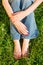 Woman in casual, sitting on green grass. Bright red manicure and