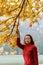 Woman casually dressed near the branches of an autumn tree