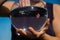 A woman catches a goldfish with her hand from a round aquarium.