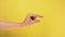 Woman caucasian hand gesture of showing small size with two fingers, isolated over yellow background. Showing small thing gesture