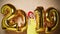 Woman celebrating New Year xmas party happy laughing in yellow sweater blouse with 2019 gold balloons