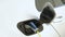 Woman charging her eco-friendly electric car at home. Closeup shot of a woman's hands plugging in her electric car