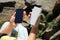 Woman charging smartphone with power bank on rocky mountain, closeup